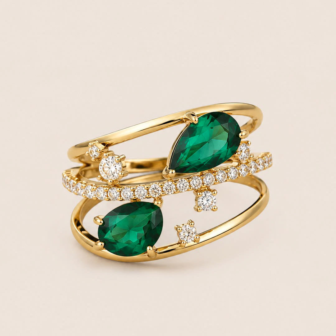 ### Bague Nebet

La **Bague Nebet** se distingue par son architecture ouverte et son éclat précieux. Confectionnée en **laiton doré**, elle est ornée de deux pierres en **nano-émeraude** taillées en forme de poire, dont le vert profond contraste élégamment avec la lumière des **zircons blancs transparents**.

Ses anneaux entrelacés dessinent une composition aérienne et contemporaine, tandis qu’une ligne de zircons illumine le centre de la bague. Les pierres ponctuelles apportent du relief et accentuent son 