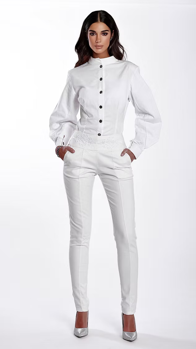 La chemise Thémis blanche est une pièce moderne et sophistiquée, brodée à la main.

Col officier.

Épaules structurées avec rembourrage et signées au nom de la maison.

Arabesques type rinceaux intrados formant une croix réalisée avec un fil métallique&nbsp; argenté qui englobent l'intégralité du dos.

Manches volumineuses aux formes exclusives de la maison, qui se clôturent par un bas de patte à double boutonnage.

Boutonnage tout le long de la chemise en acier inoxydable.

Coton bio noble, épais et opaque