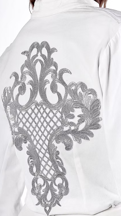 La chemise Thémis blanche est une pièce moderne et sophistiquée, brodée à la main.  Col officier.  Épaules structurées avec rembourrage et signées au nom de la maison.  Arabesques type rinceaux intrados formant une croix