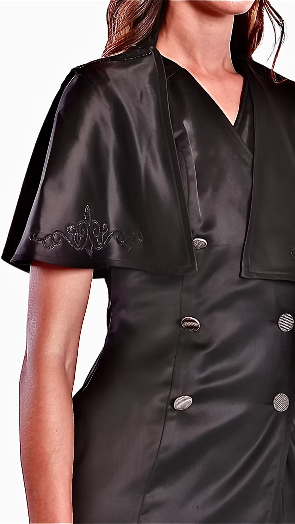 La robe croisée blazer Astérope noire avec sa cape intégrée et brodée, ton sur ton est proposée en sur-mesure.

Demi-col officier au dos.

Encolure en V à l’avant.

Épaules structurées et signées au nom de la maison.

Cape circulaire courte intégrée au corps de la robe, qui présente des arabesques au niveau de la poitrine, ton sur ton et un soufflet au dos.

Double boutonnage en acier inoxydable accompagné d’un bouton transparent à l’intérieur.

Robe arrivant à mi-cuisse.

Soie naturelle d’un fini mat.

Cou