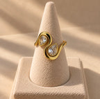 Anillo dorado con dos gotas transparentes sobre expositor