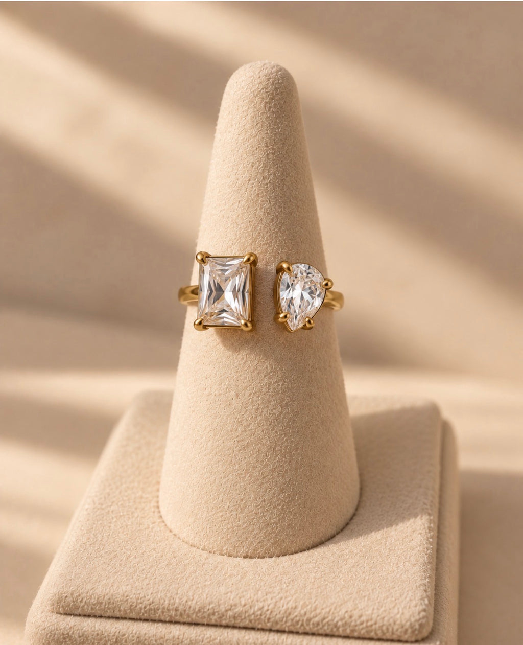 Bague dorée à deux pierres transparentes sur présentoir