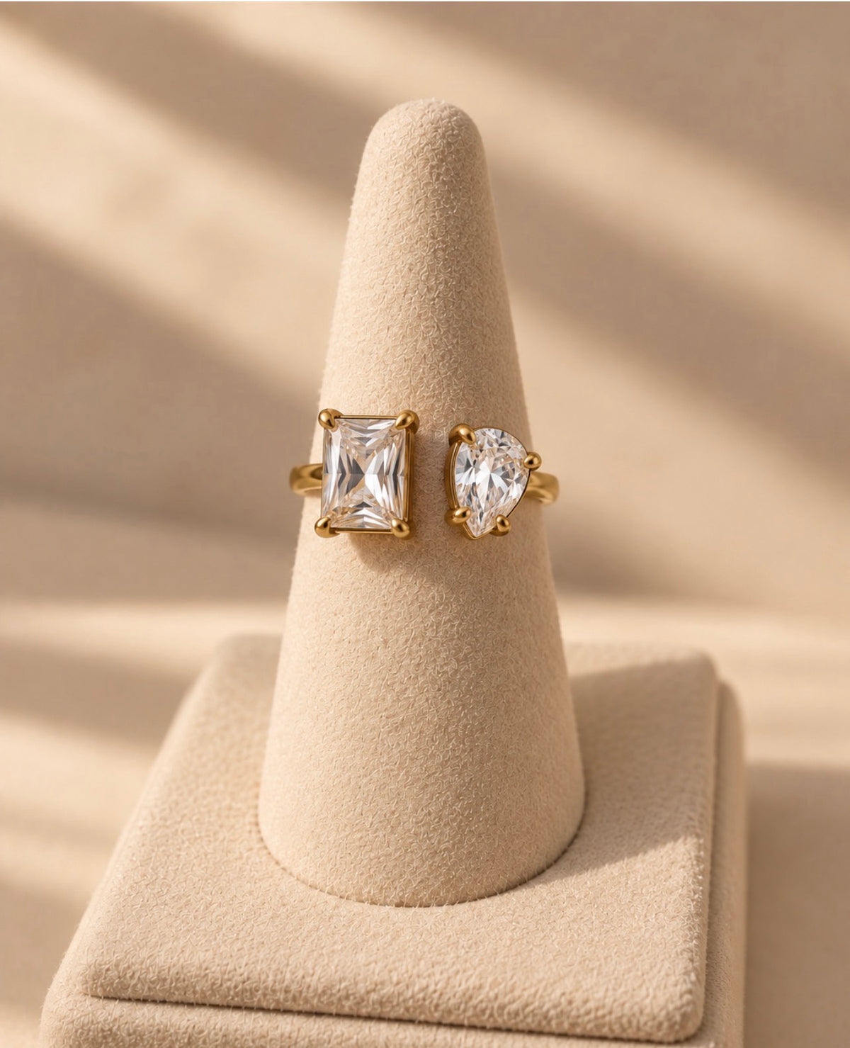 Bague dorée à deux pierres transparentes sur présentoir