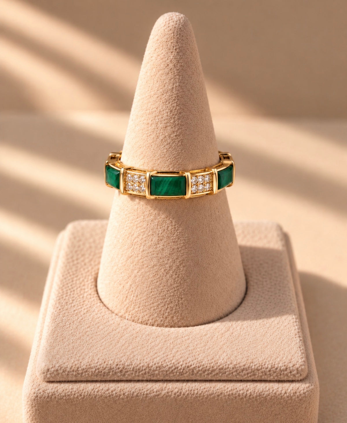 Bague dorée à maillons verts sur présentoir conique