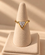 Anillo dorado con piedra triangular sobre expositor cónico