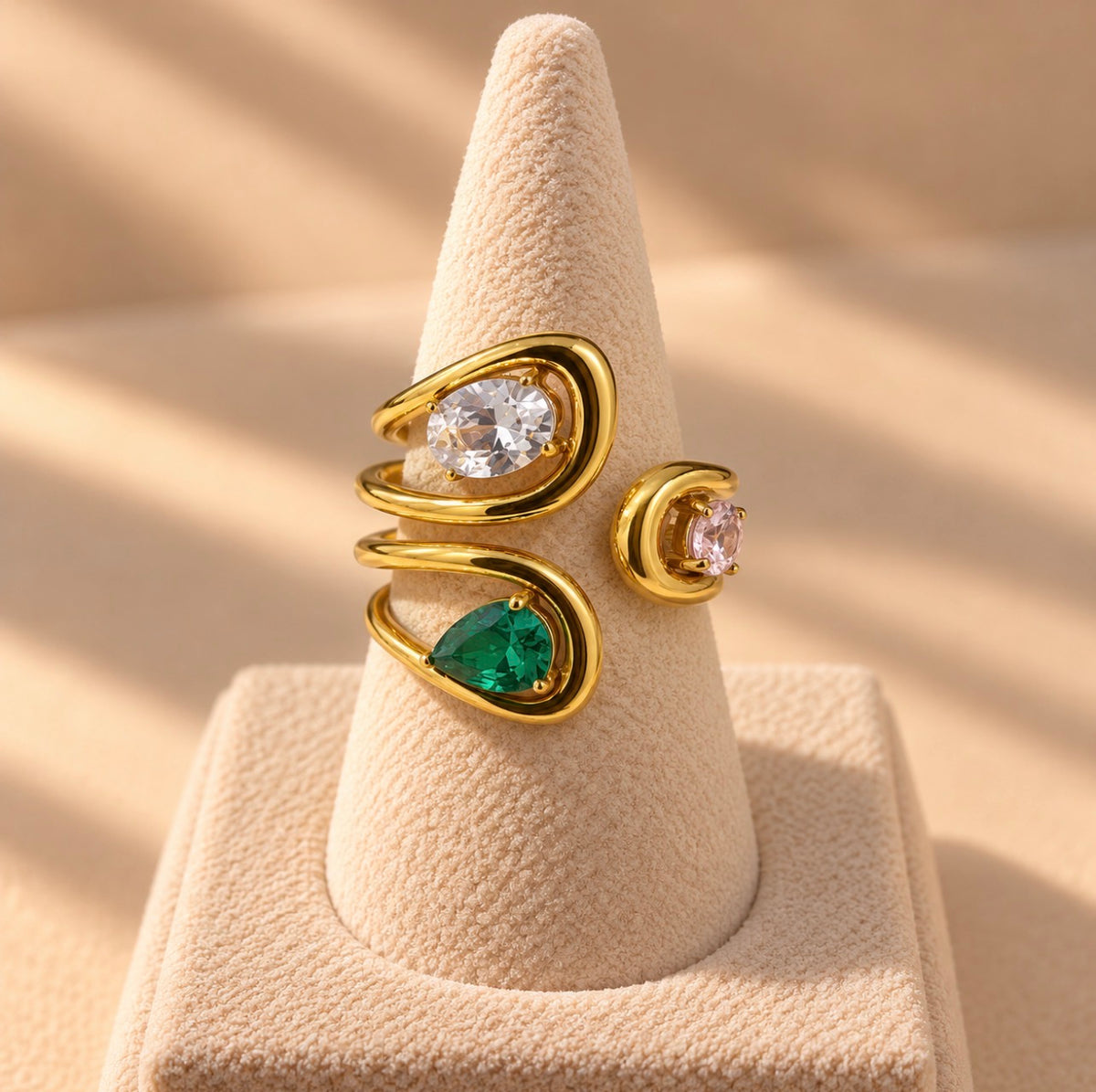 Bague dorée à trois pierres colorées sur présentoir