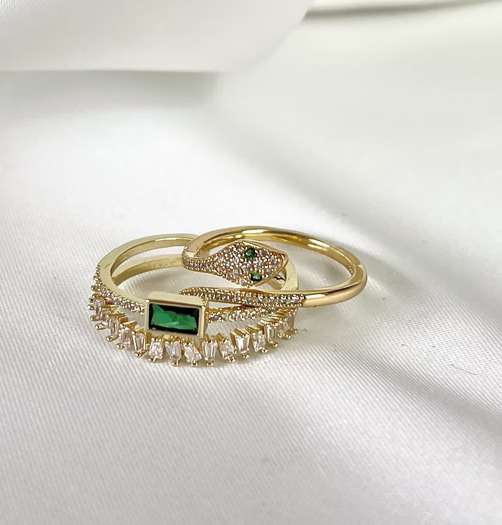 Anello dorato decorato con pietre appoggiato su tessuto bianco