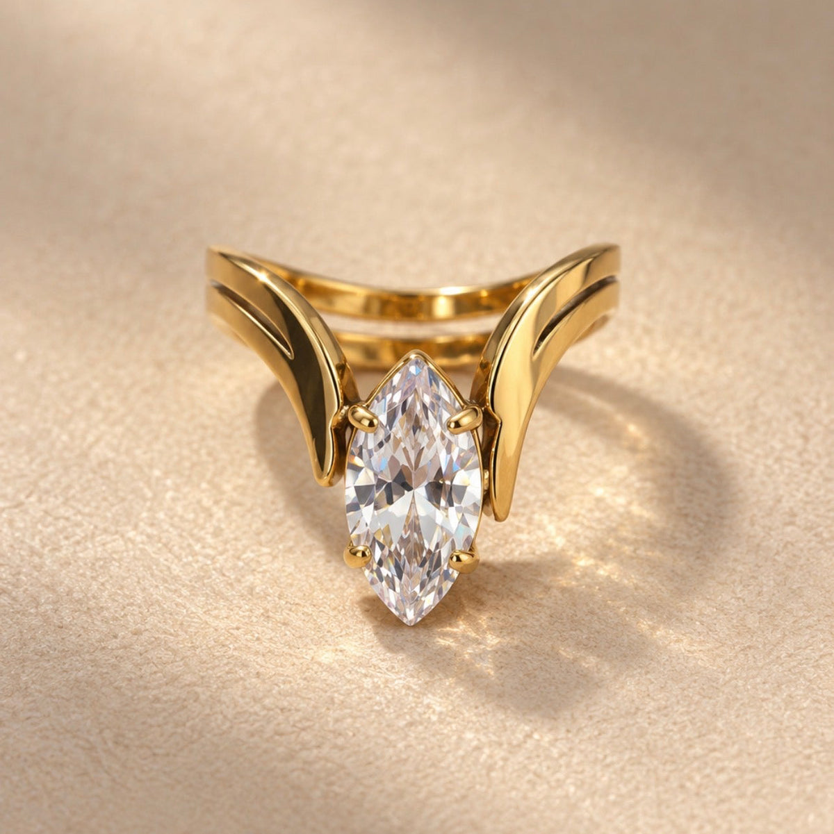 Bague dorée sculptée autour d’une pierre navette transparente