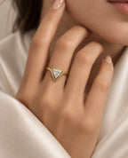 Anillo dorado triangular junto al rostro