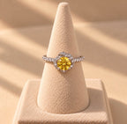 Bague Tefnout sur un présentoir beige, en argent 925 avec nano saphir jaune central et anneau orné de cristaux.