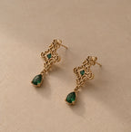 Boucles dorées à arabesques et gouttes vertes sur pierre