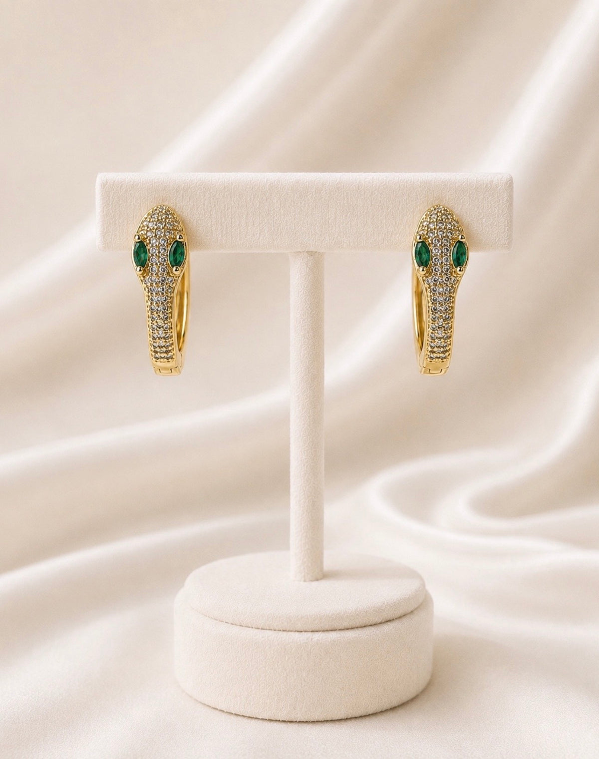 Boucles dorées allongées serties de vert sur présentoir