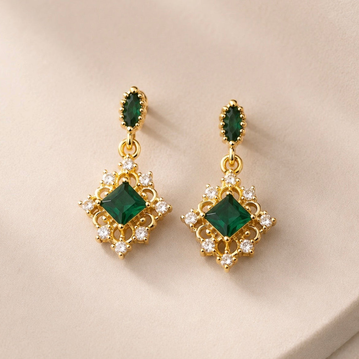 Boucles dorées pendantes aux pierres vertes sur fond clair