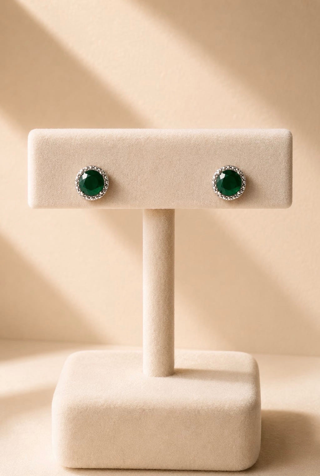 Boucles rondes vertes serties sur un présentoir beige
