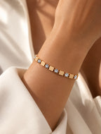 Bracelet doré à maillons carrés porté au poignet