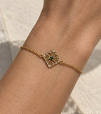 Pulsera dorada con motivo cuadrado calado en la muñeca