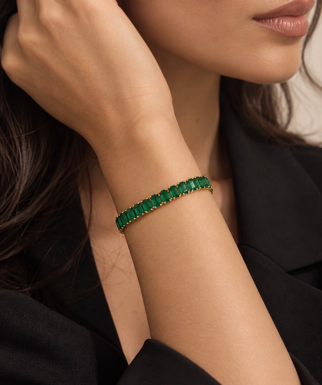 Bracelet doré à rangée de pierres vertes porté