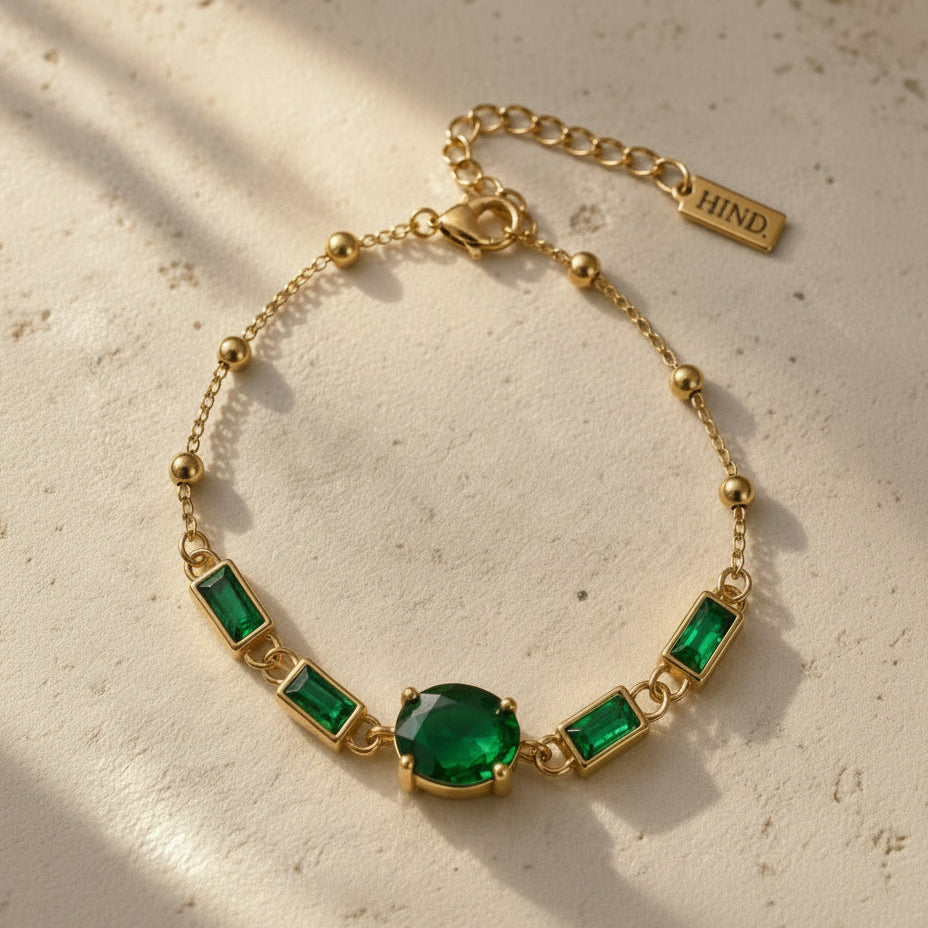 Bracelet doré aux pierres vertes sur pierre claire