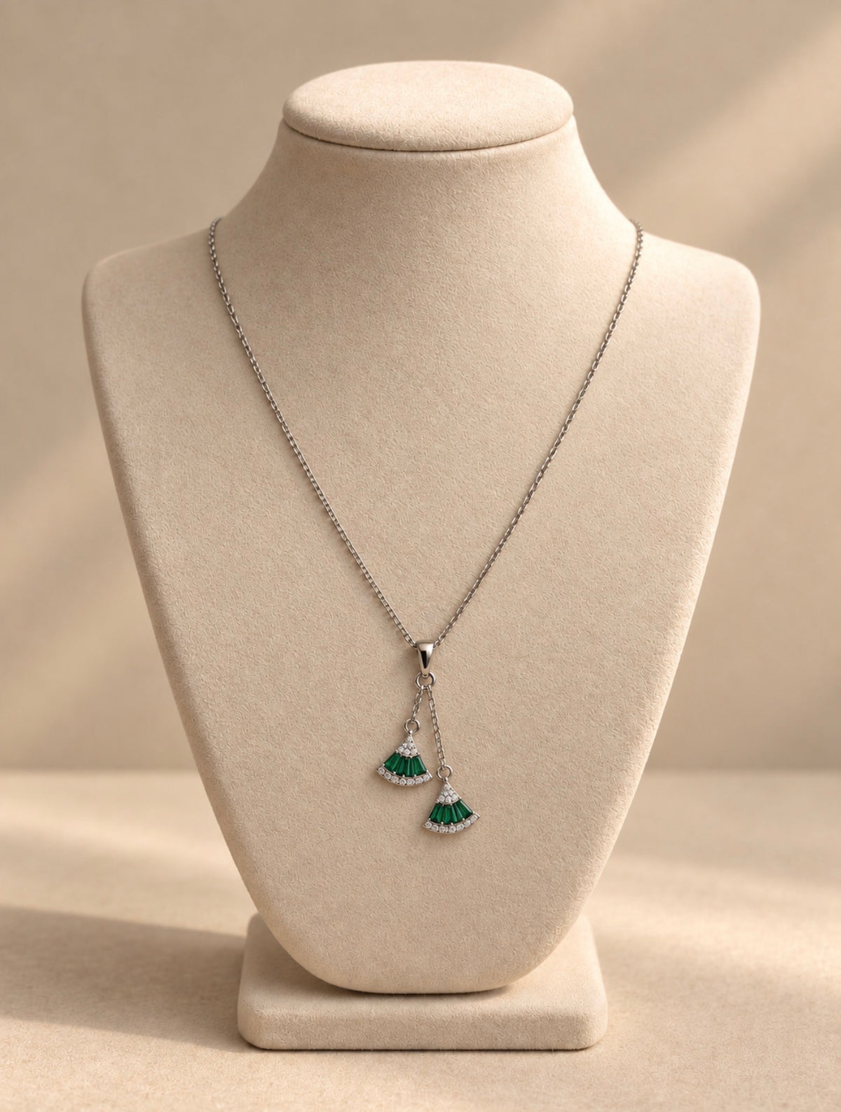 Collier Anat Argenté en argent 925, deux pendentifs en éventail vert nano émeraude, présenté sur un buste crème.
