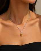 Collier argenté à pierre jaune porté au cou
