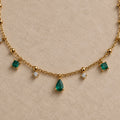 Détail du collier Arsinoé doré à l’or 18 carats, avec pampilles nano émeraude, cristaux et goutte verte centrale.