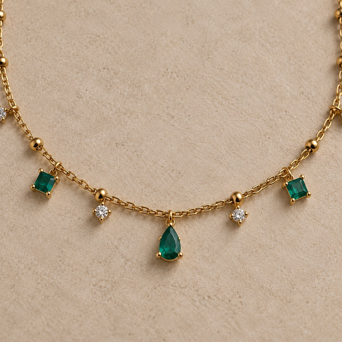 Détail du collier Arsinoé doré à l’or 18 carats, avec pampilles nano émeraude, cristaux et goutte verte centrale.