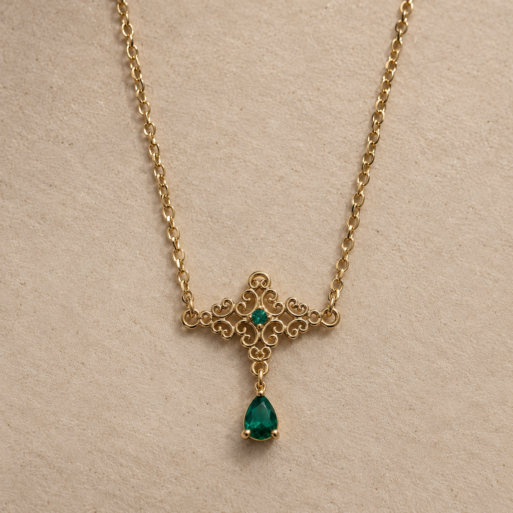 Collier Cléopâtre doré, arabesques et pendentif en goutte verte, vue de près sur fond beige