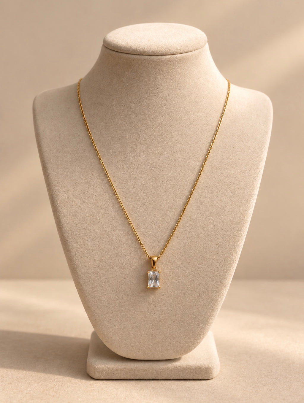 Collar dorado con piedra transparente sobre busto beige