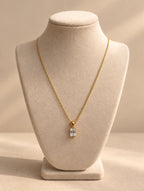 Collar dorado con piedra transparente sobre busto beige