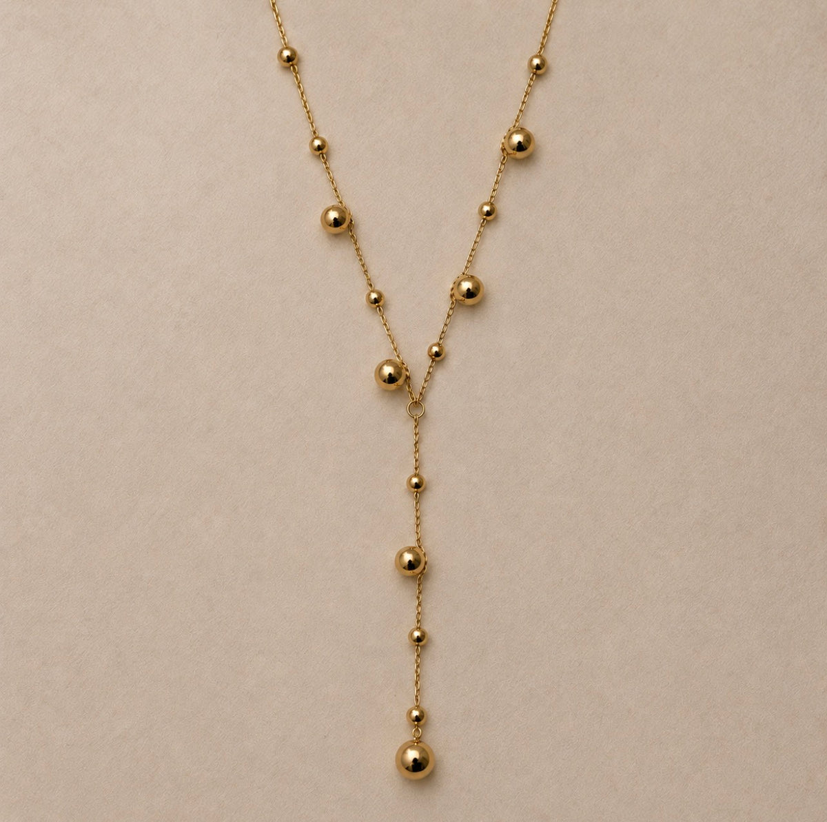 Détail de la chaîne fine et des boules dorées du Collier Néfertari, avec sa retombée centrale en Y.