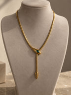 Collier serpent doré à pierre verte sur présentoir