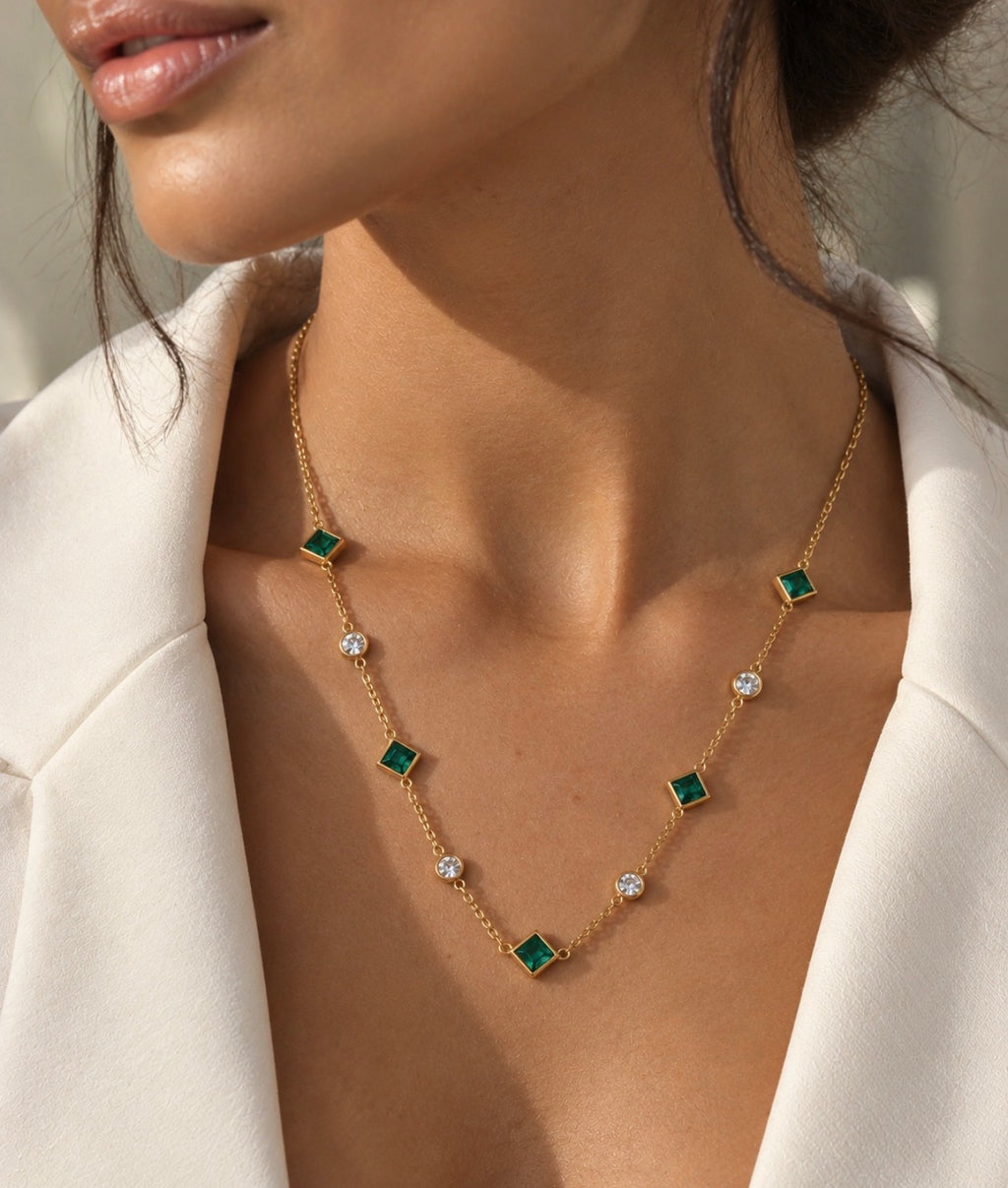 Collar Tiyi bañado en oro de 18 quilates, nanoesmeralda y cristal, en el cuello con camisa blanca.