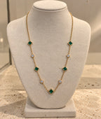 Collar Tiyi de latón bañado en oro de 18 quilates, nanoesmeralda y cristal, sobre busto crema.