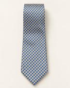 Cravate Auber en jacquard de soie à damier bleu et champagne doré, présentée à plat sur fond clair.