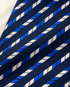 Gros plan du jacquard Cambon : segments bleu royal et blancs alignés en diagonale sur une trame bleu marine texturée.