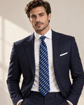 Cravate Cambon à rayures bleues et blanches, portée avec un costume bleu marine, une chemise blanche et une pochette blanche.