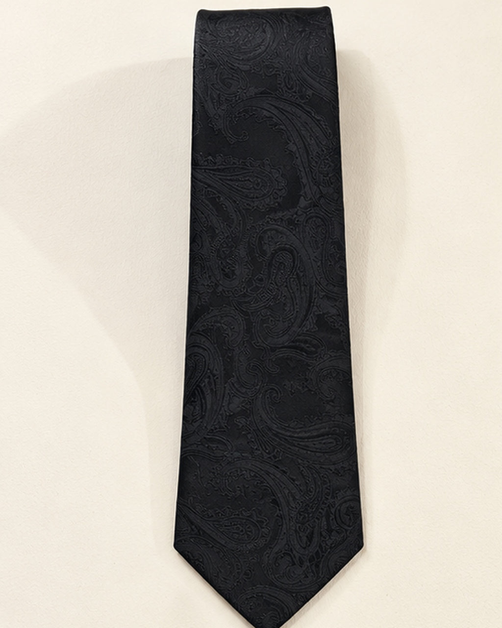 Cravate Castiglione en jacquard de soie noir présentée à plat, ornée de grands motifs cachemire ton sur ton.
