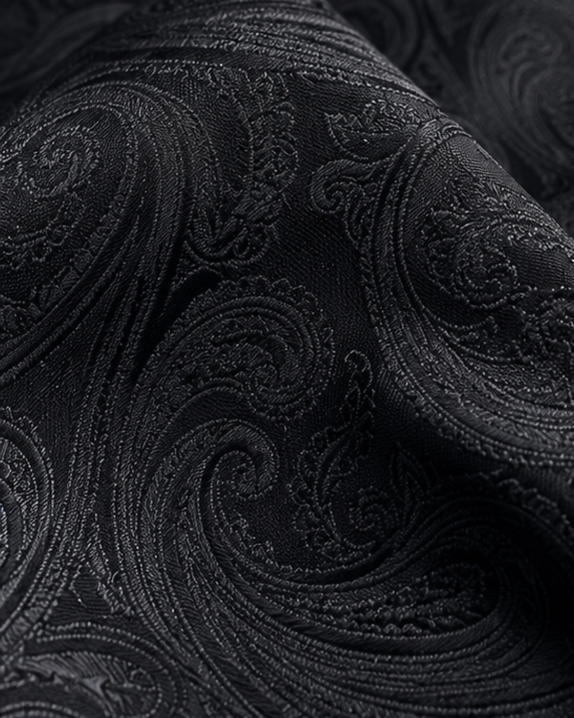 Gros plan du jacquard de soie Castiglione, motifs cachemire noirs aux contours satinés et reflets anthracite.