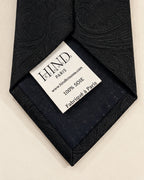 Dos de la cravate Castiglione noire, doublure sombre et étiquette Hind Kroussa Paris indiquant 100 % soie et fabriqué à Paris.