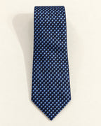 Cravate Caumartin en jacquard de soie, à petits carreaux bleu marine, bleu ciel et noirs, présentée à plat.