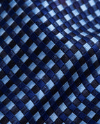 Gros plan du jacquard de soie Caumartin : damier de petits carreaux bleu ciel, bleu marine et noirs aux reflets satinés.