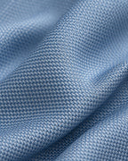 Gros plan du jacquard de soie Chaptal : petits motifs tissés bleu ciel aux reflets clairs.