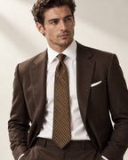 Cravate Duras brun et bronze, portée avec un costume chocolat, une chemise blanche et une pochette blanche.