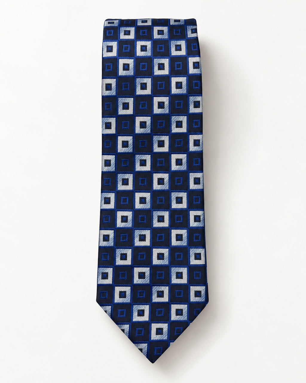 Cravate Gramont en jacquard de soie présentée à plat, ornée de carrés emboîtés bleu marine, bleu royal et gris argenté.