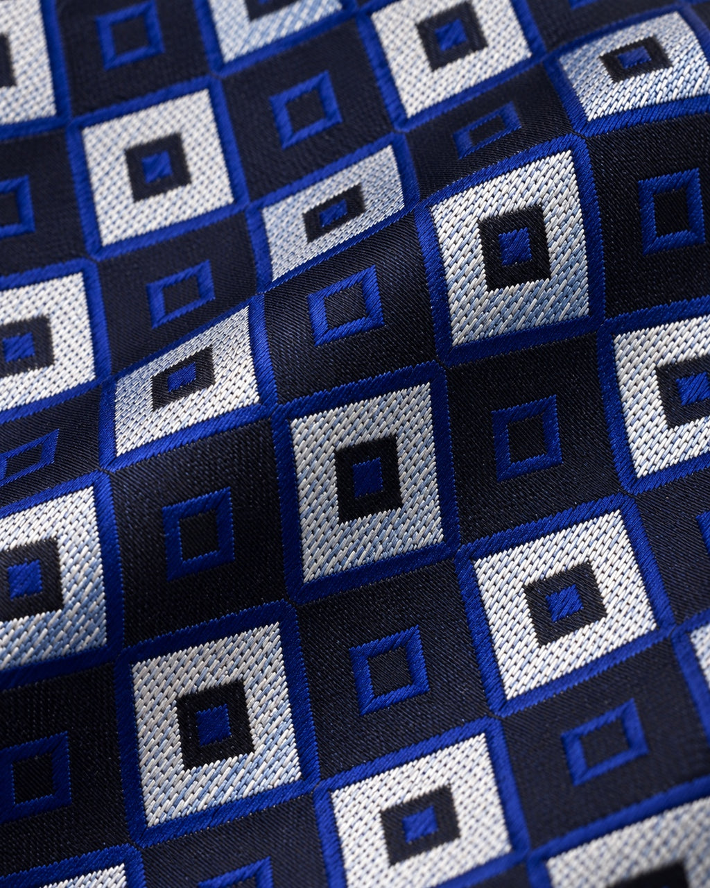 Détail du jacquard Gramont : carrés gris argenté texturés alternant avec des carrés sombres soulignés de bleu royal.