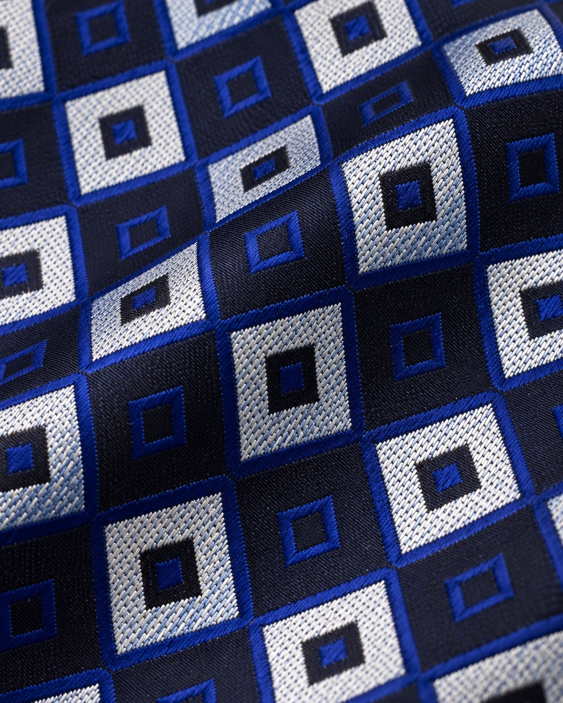 Détail du jacquard Gramont : carrés gris argenté texturés alternant avec des carrés sombres soulignés de bleu royal.