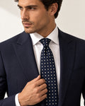 Cravate Laborde bleu marine à carreaux et losanges ivoire, portée avec un costume marine et une chemise blanche