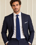 Cravate Lavoisier bleu marine à petits motifs ivoire, portée avec un costume marine et une chemise blanche.