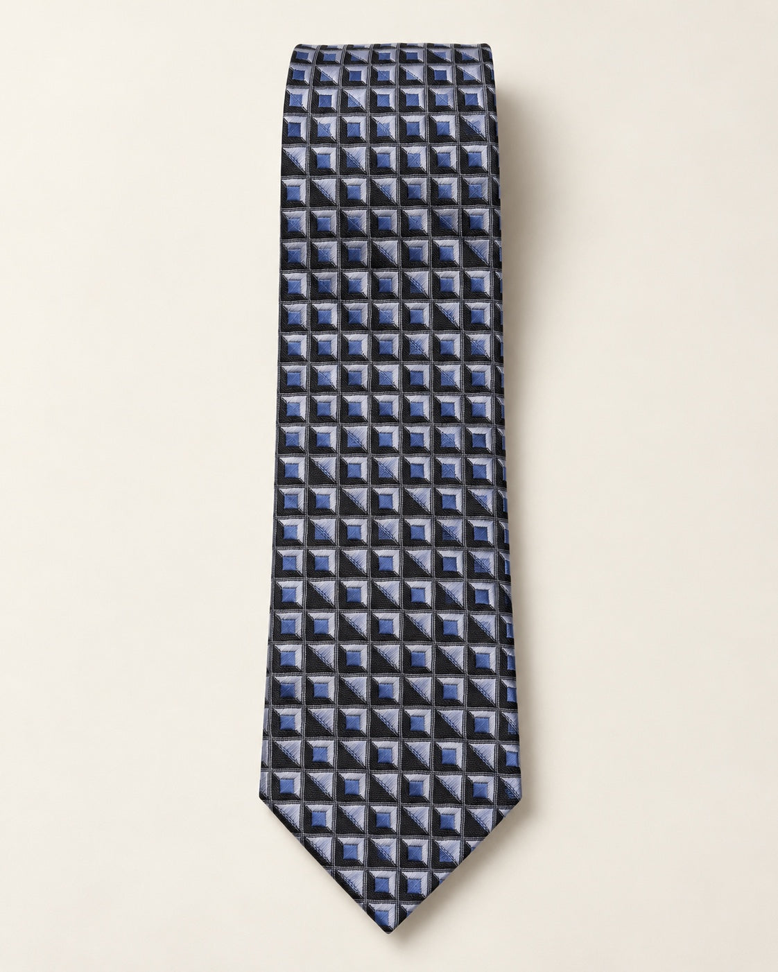 Cravate Marignan en jacquard de soie présentée à plat, à carrés bleus facettés et triangles gris argenté sur fond noir.
