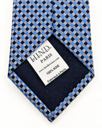 Dos de la cravate Marivaux à damier bleu, doublure marine et étiquette Hind Kroussa Paris indiquant 100 % soie.
